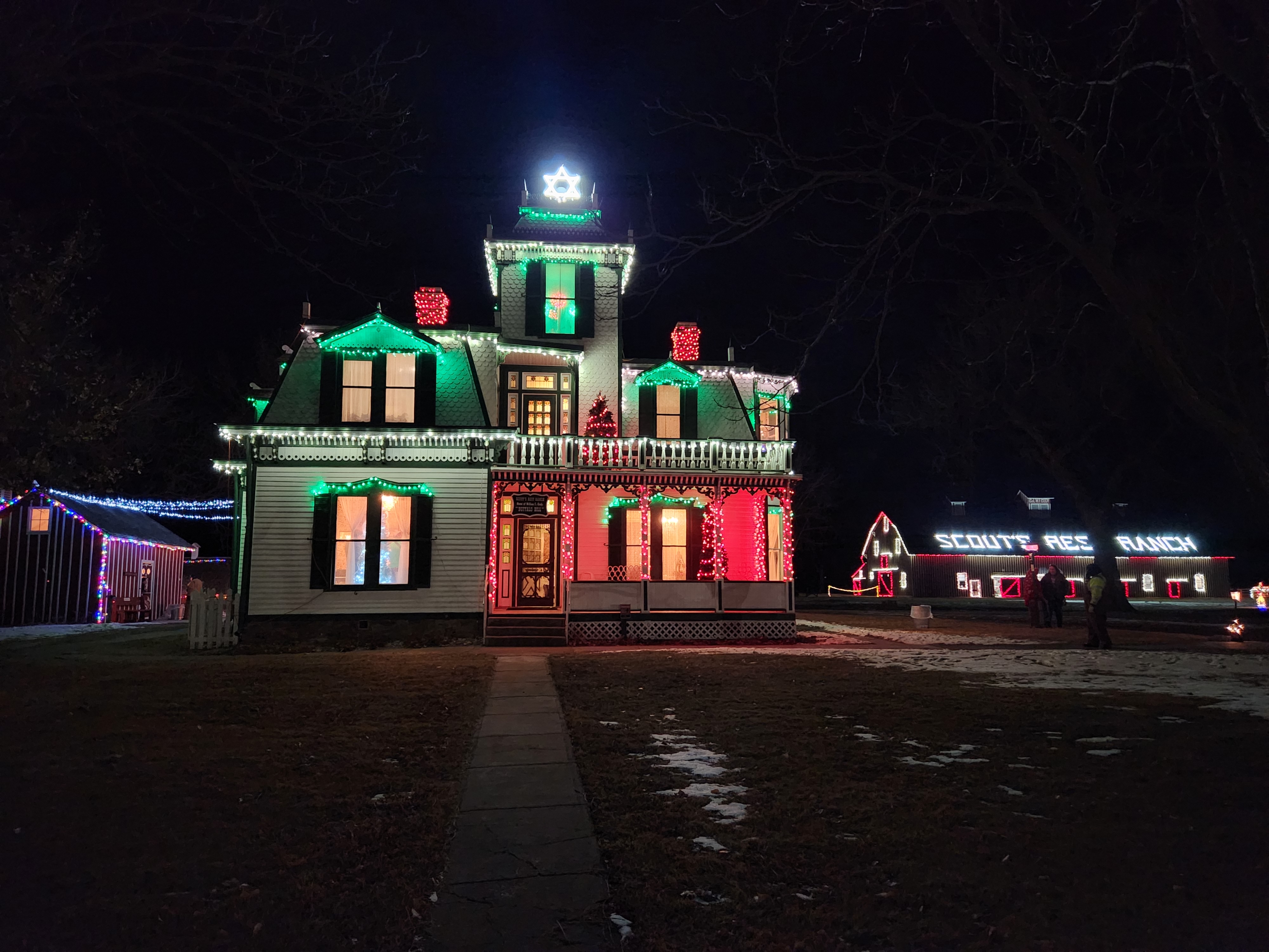 Outside of a historical house with Christmas lights decorating it.