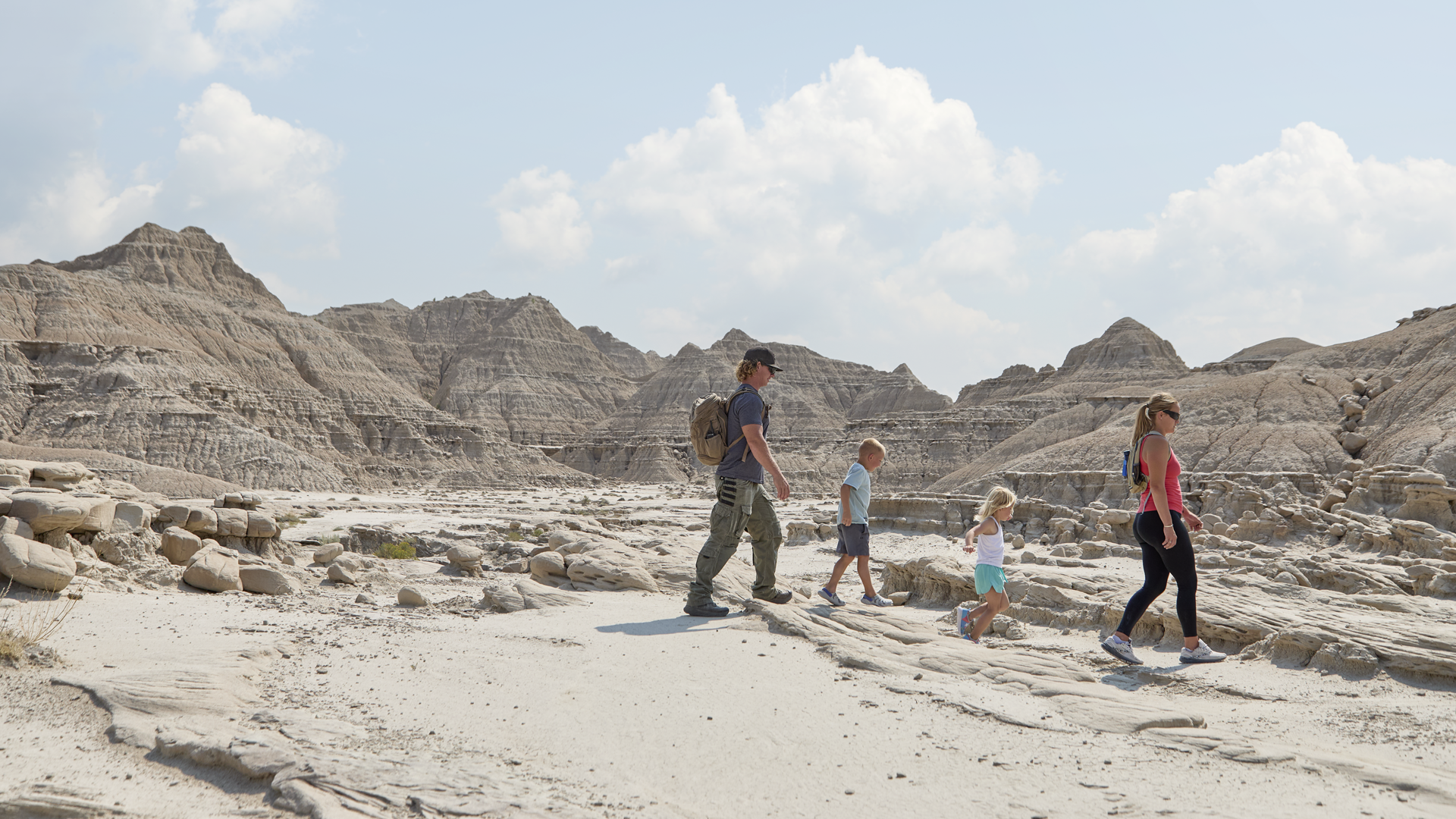 A family walking through the otherworldly landscapes of Toadstool Geologic Park.