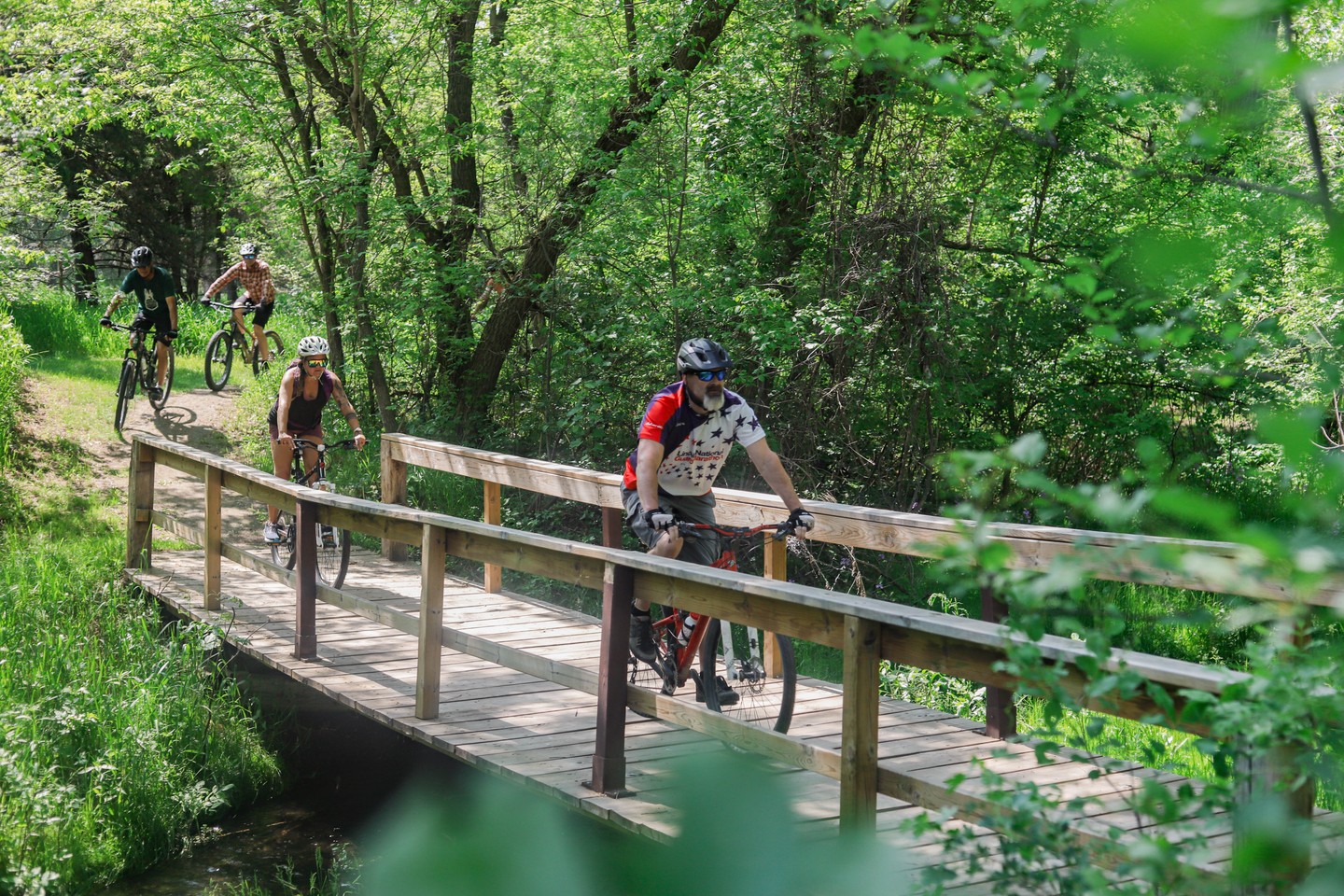 A cyclist on a bridge surrounded by greenery at Chadron State Park.