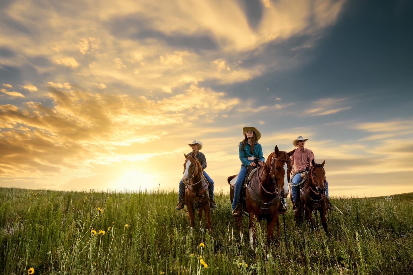 Three horseback riders on the Nebraska plains at sunset with Calamus Outfitters.
