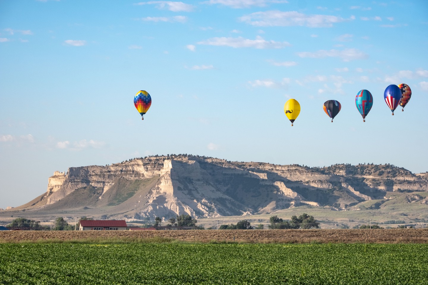 Hot-air balloons floating over Nebraska with Scotts Bluff National Monument in the background as part of Old West Balloon Fest.