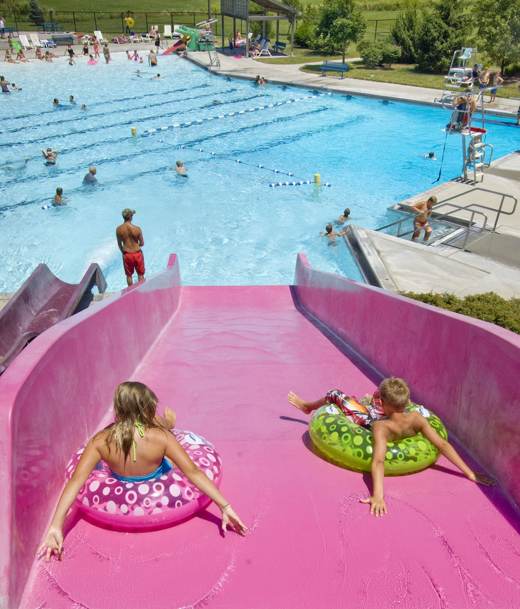 Two kids sit on inner tubes and get ready to zoom down a steep, pink waterslide at Beatrice Big Blue Water Park near Beatrice, NE.