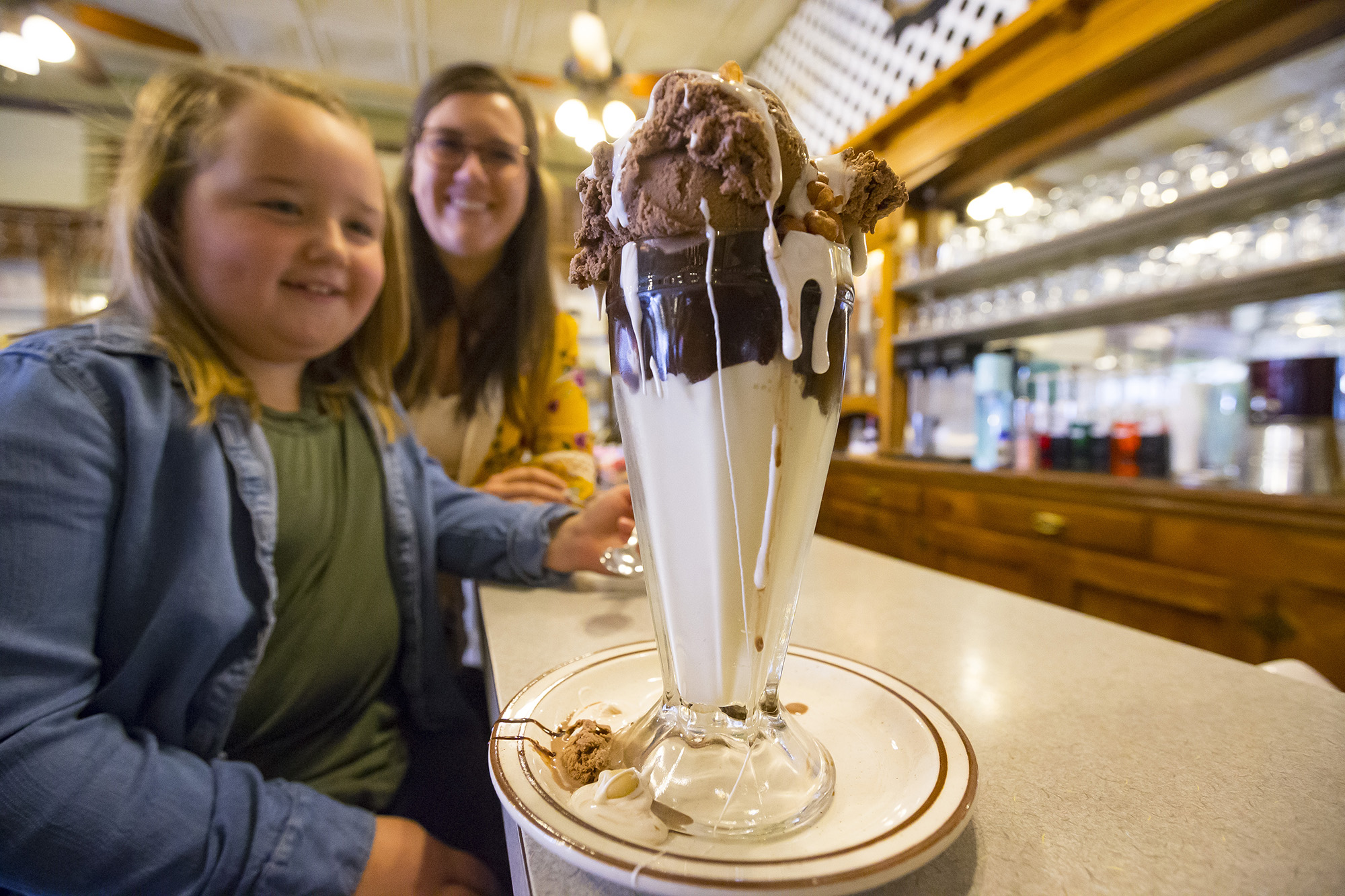 A mother and child look at the original Tin Roof Sundae on the counter at The Potter Sundry.