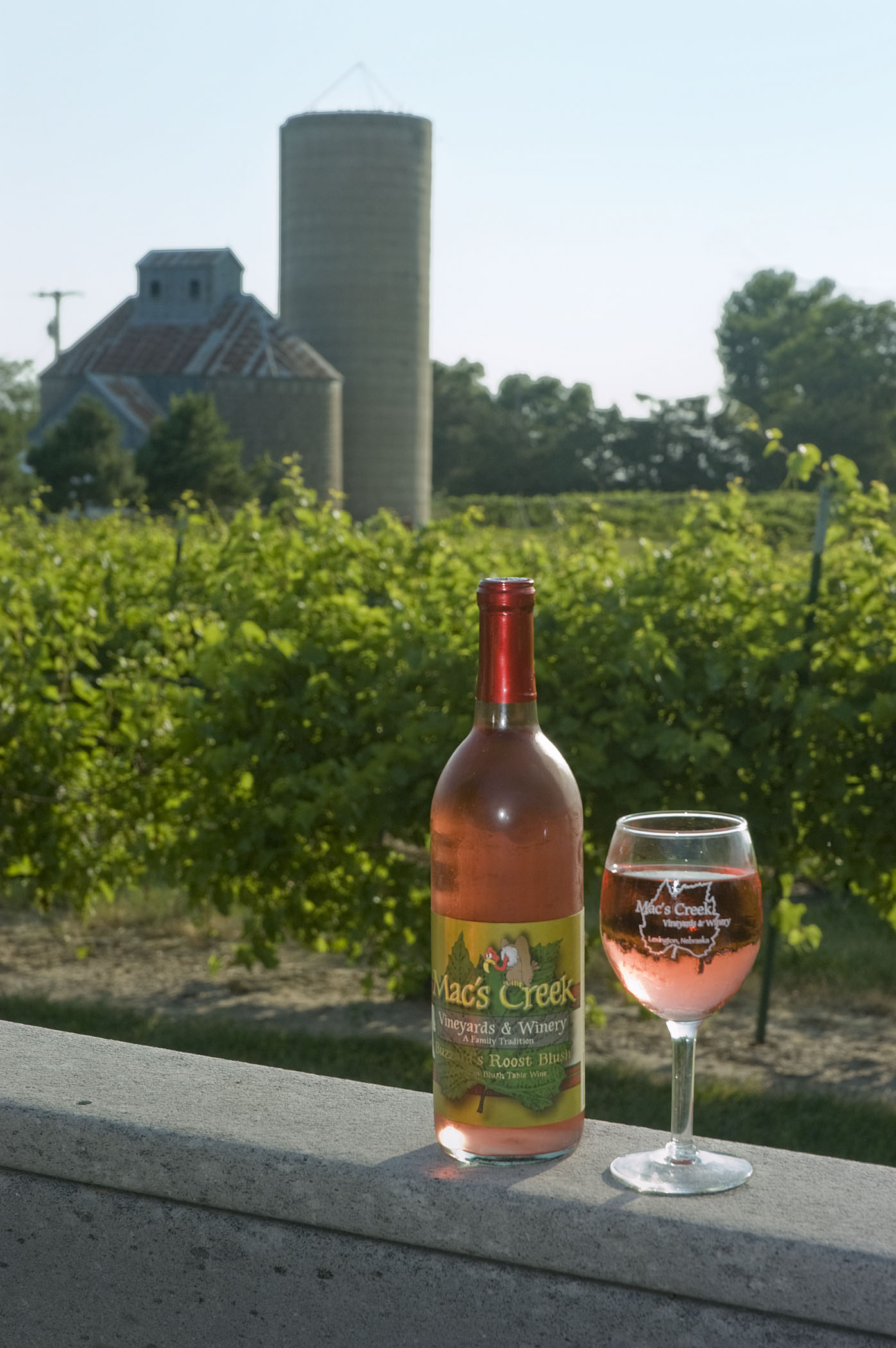 A bottle of wine next to a full glass outside Mac's Creek Winery.