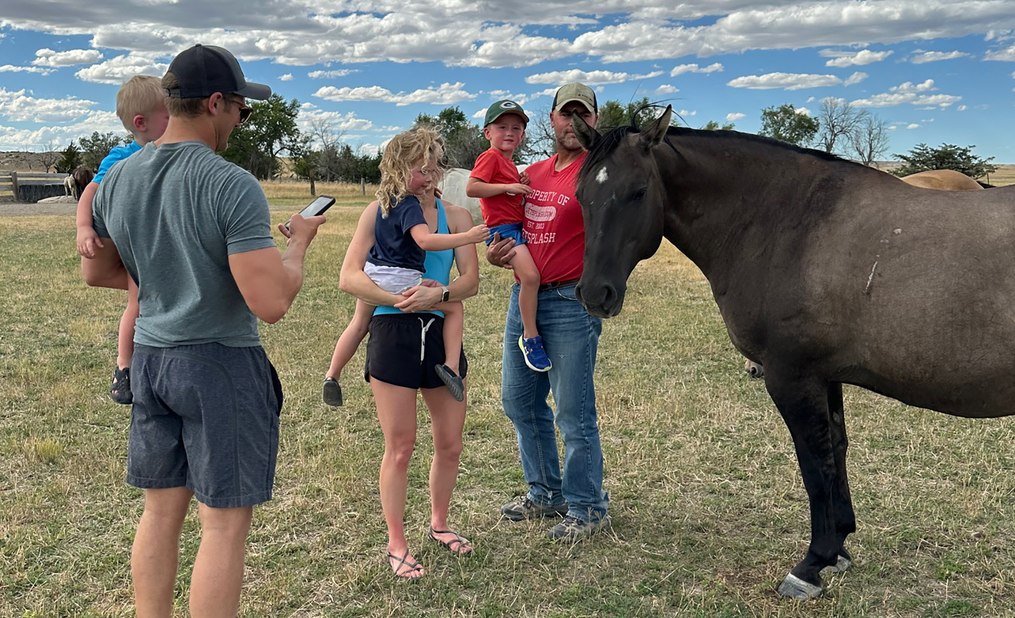 Families gather around a horse at Our Heritage Guest Ranch.