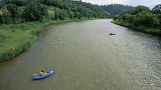 Two kayakers explore the lush banks of the Niobrara National Scenic River in Nebraska.